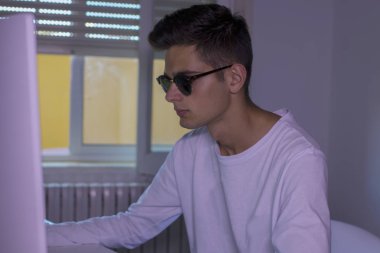 Genç evde bilgisayar ve cep telefonu ile