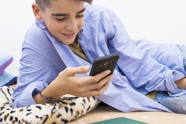 child with a mobile phone lying at home