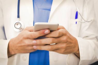 Doktorun elinde cep telefonu ile tıp