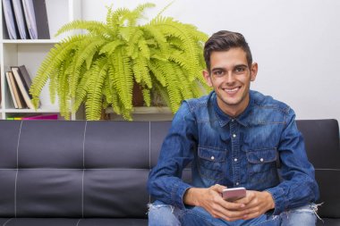 cep telefonu ile kanepede oturan genç adam