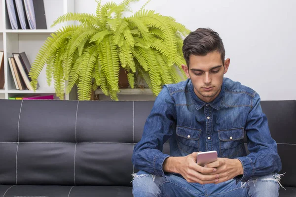 Jeune Homme Assis Sur Canapé Avec Téléphone Portable — Photo