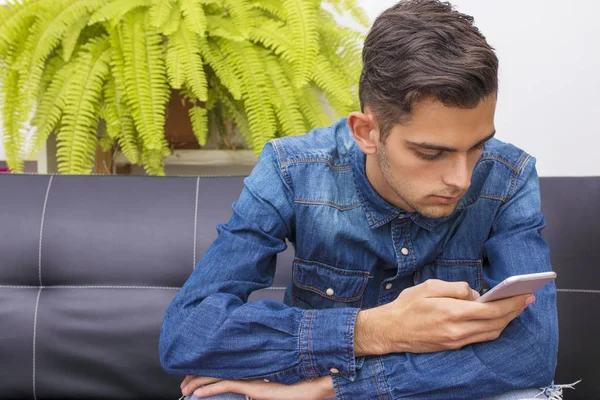 Jovem Sentado Sofá Com Telefone Celular — Fotografia de Stock