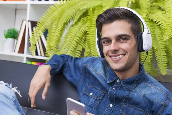 Jongeman Luisteren Naar Muziek Home Lounge Met Telefoon Oortelefoons — Stockfoto