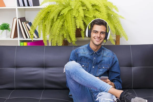 Joven Escuchando Música Hogar Salón Con Teléfono Auriculares — Foto de Stock