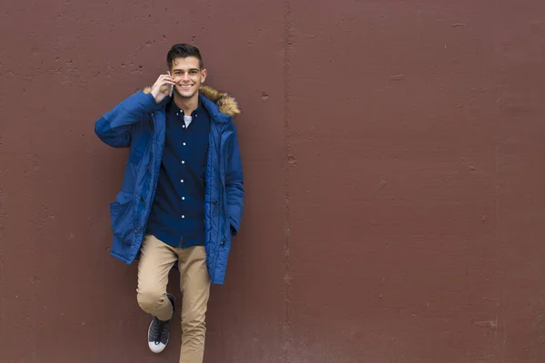 young man on the wall with outdoor mobile phone