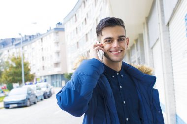 genç adam üstünde hareket eden telefon şehir sokak konuşuyor