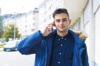 genç adam üstünde hareket eden telefon şehir sokak konuşuyor