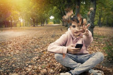 genç genç sonbaharda parkta cep telefonu ile