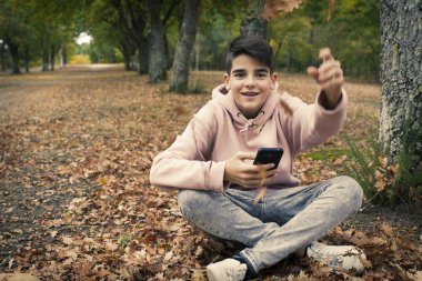 genç genç sonbaharda parkta cep telefonu ile