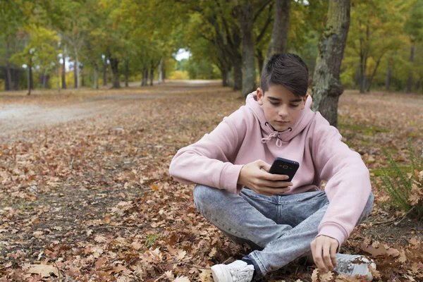 秋の公園で携帯電話で若いティーンエイ ジャー — ストック写真