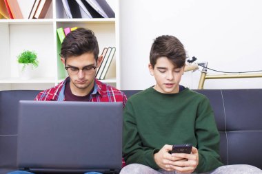 bilgisayar ve cep telefonu evde kanepede gençlerle
