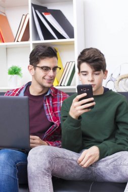 bilgisayar ve cep telefonu ile evde gençler