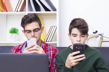 bilgisayar ve cep telefonu ile evde gençler