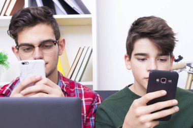 bilgisayar ve cep telefonu ile evde gençler