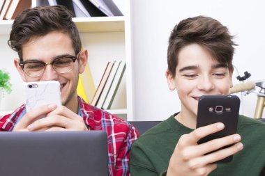 bilgisayar ve cep telefonu ile evde gençler