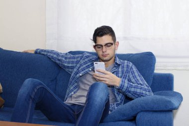 Daire kanepe üstünde hareket eden telefon ile genç adam