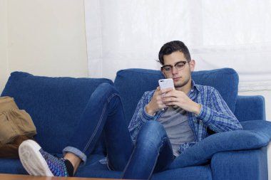 Daire kanepe üstünde hareket eden telefon ile genç adam