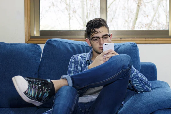 年轻的休闲在家庭沙发用手机 — 图库照片