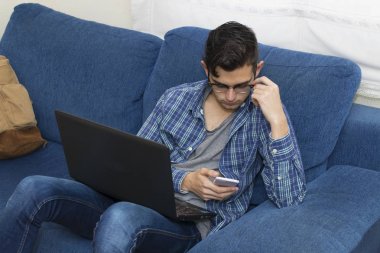 cep telefonu ve laptop ile ev kanepe genç