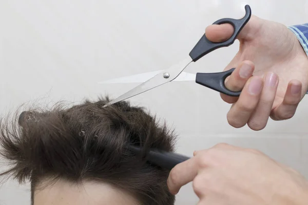 hands with hairdressing scissors cutting hair, barber