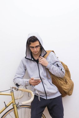 sırt çantası ve beyaz duvar üstünde hareket eden telefon ile genç