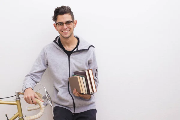 fashion student with books and bike on the wall