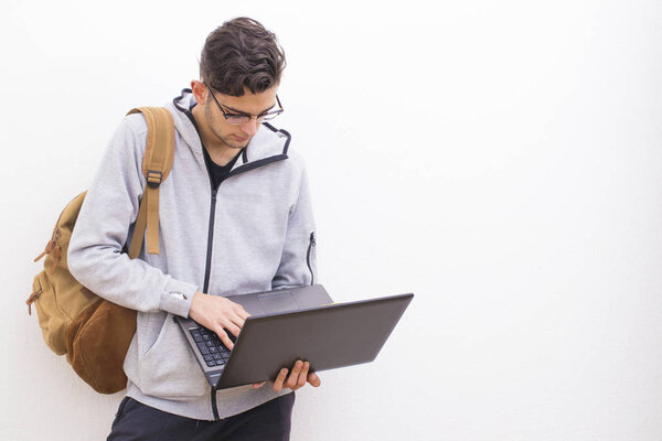 student or young adult with laptop on the white wall with space