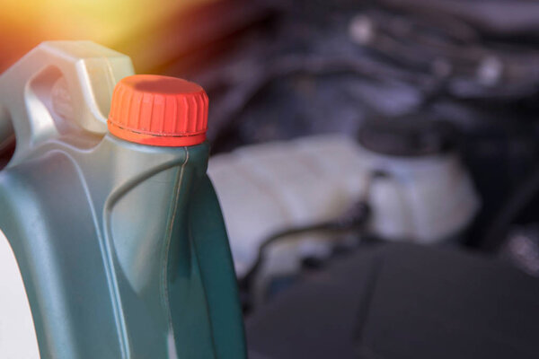 bottle of lubricant or engine oil with the bottom of the car engine