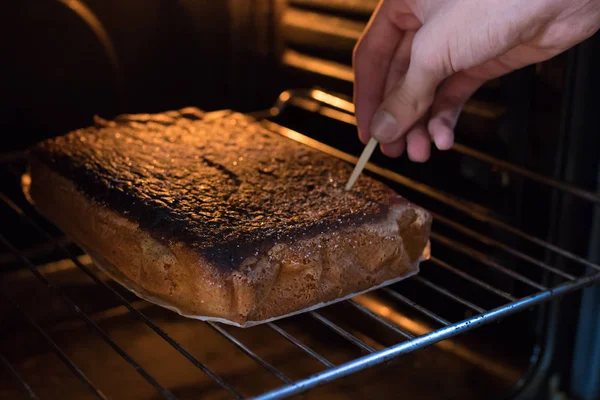 cake or dessert in the oven by hand checking the cooking