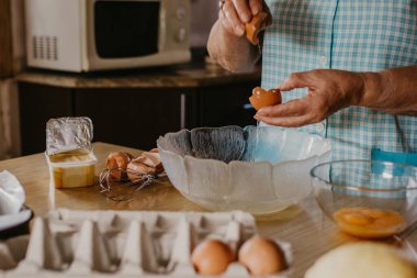 Yaşlı bir kadının elleri yumurta, kek ve tatlı hazırlıyor.
