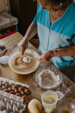 Yetişkin bir kadın mutfakta tatlı ve tatlı karışımını yoğuruyor.