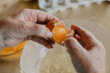 Yaşlı bir kadının elleri yumurta, kek ve tatlı hazırlıyor.