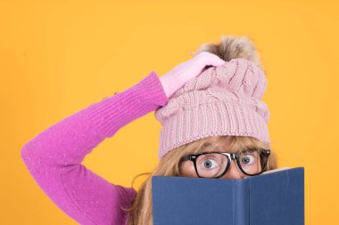 Şapkası, kitabı ve hayranlık ifadesi olan ve açık kitapla sürpriz yapan bir kadın.