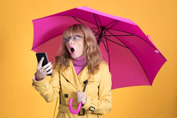Şemsiyeli Yetişkin Bir Kadın Cep Telefonuna Şaşkınlıkla Bakıyor — Stok fotoğraf