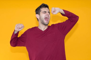 Genç adam uykusunda esniyor. Renkli arka planda.