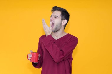 Yalnız genç bir adam esniyor ya da renk arka planında uyanıyor.