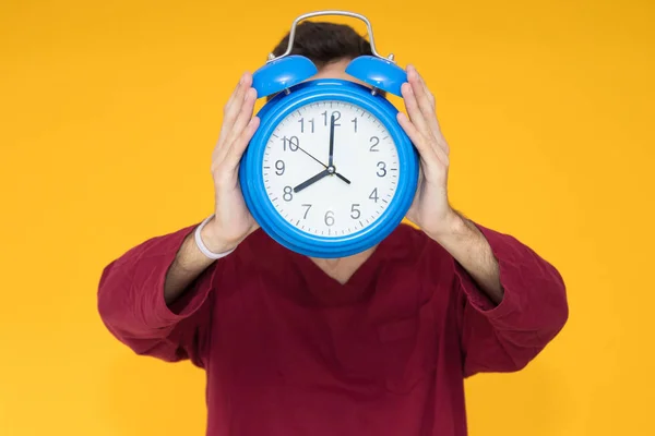 young man with alarm clock over color background