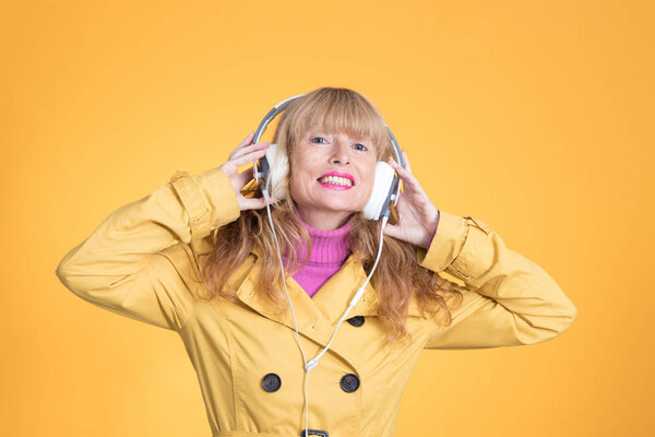 adult woman with headphones dancing on color background