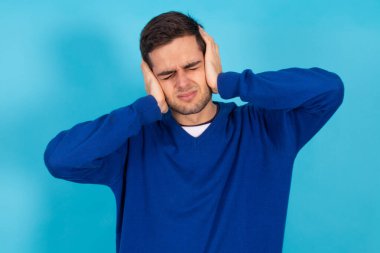 young man isolated on blue background with hands on his head