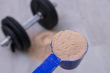 Spor salonunda protein tozu ve dambıl.