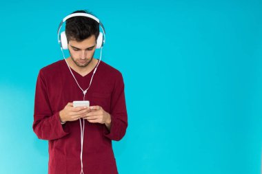 Akıllı telefonu ya da cep telefonu kulaklığı olan genç adam renk arkaplanında izole edildi