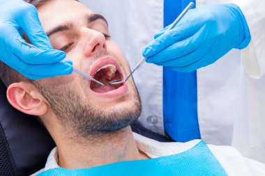 Dişçi aletleri ile hastanın ağzı üzerinde çalışıyor.