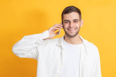 Renk arka plan üstünde hareket eden telefon ile genç adam portresi