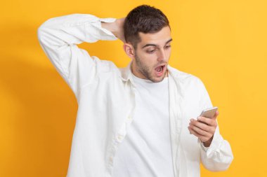 Cep telefonuna bakan şaşırmış yüzlü genç adam.