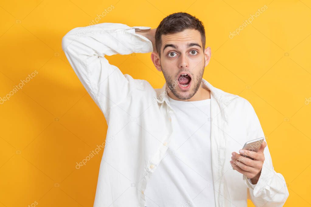 surprised young man with mobile phone isolated on color background