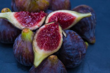 Doğal siyah incirler gruplandırılmış ve siyah arkaplanda açılır