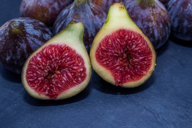 Doğal siyah incirler gruplandırılmış ve siyah arkaplanda açılır