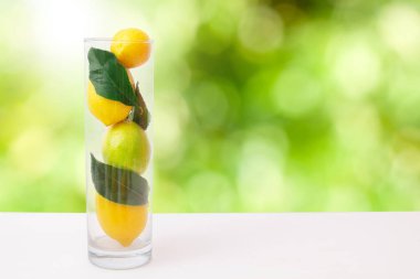 Yaprakları ve yeşil arka planı olan bir sürahi doğal limon.