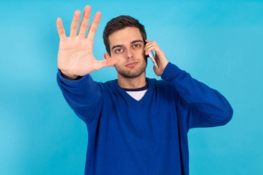 Cep telefonlu sıradan bir genç hippi. Renkli arka planda izole edilmiş.