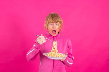 adult woman with plate of pasta and sportswear isolated on color background